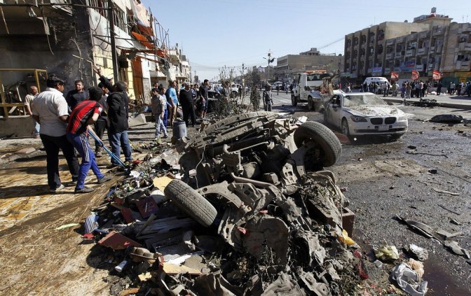 Residents gather at the site of a car bomb attack in the AL-Mashtal district in Baghdad