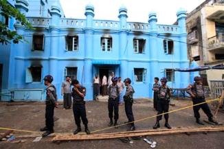 Police stand in front of a mosque and school dormitory that were damaged by a fire in Yangon