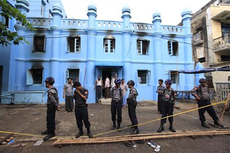 Police stand in front of a mosque and school dormitory that were damaged by a fire in Yangon