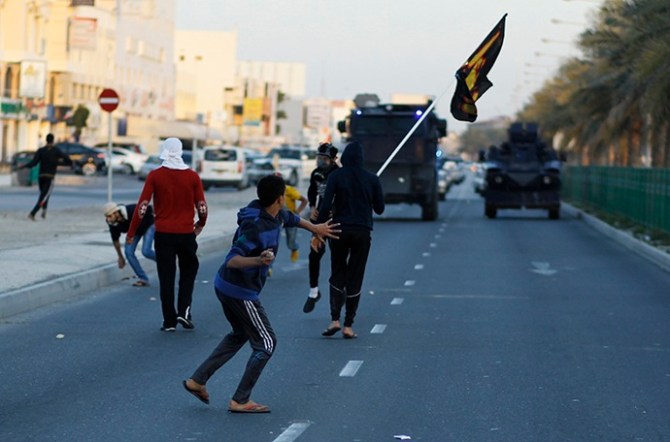 Anti-government protesters throw stones at riot police after the funeral procession for Asma Hussain, in the village of Jid Al Haj
