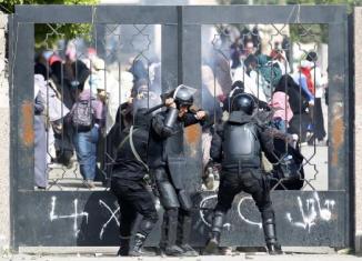 Riot police attempt to break open the entrance of the al-Azhar University Campus during clashes in Cairo