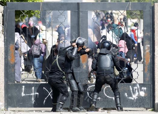 Riot police attempt to break open the entrance of the al-Azhar University Campus during clashes in Cairo