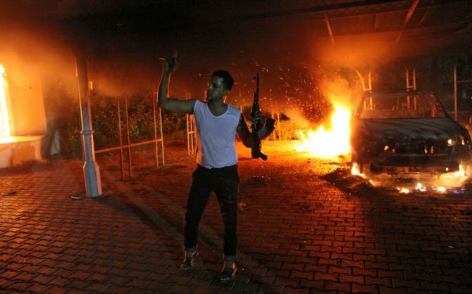 An armed man waves his rifle as building