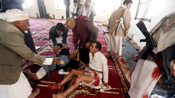 People react after being injured in bomb attack inside a mosque in Sanaa